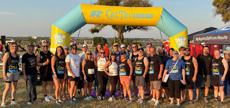 Athletes and supporters under a Cal Tri Events finish-line arch